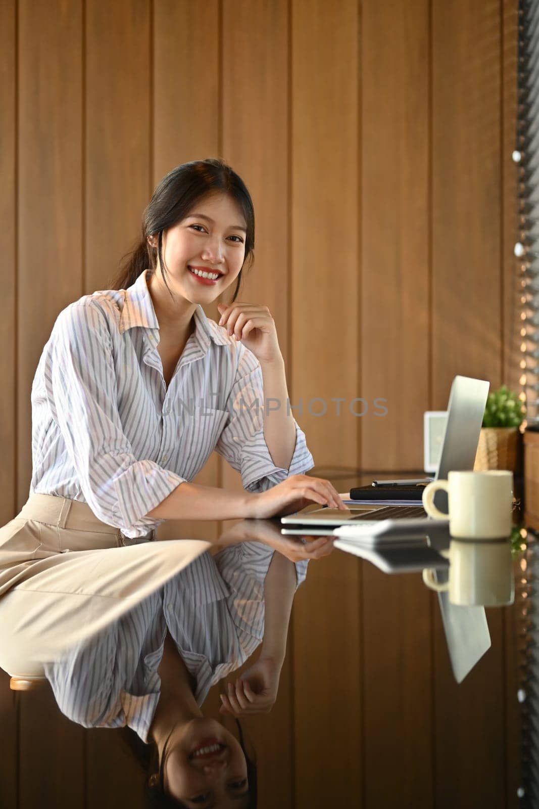 Portrait of confident young businesswoman using laptop computer at workplace.