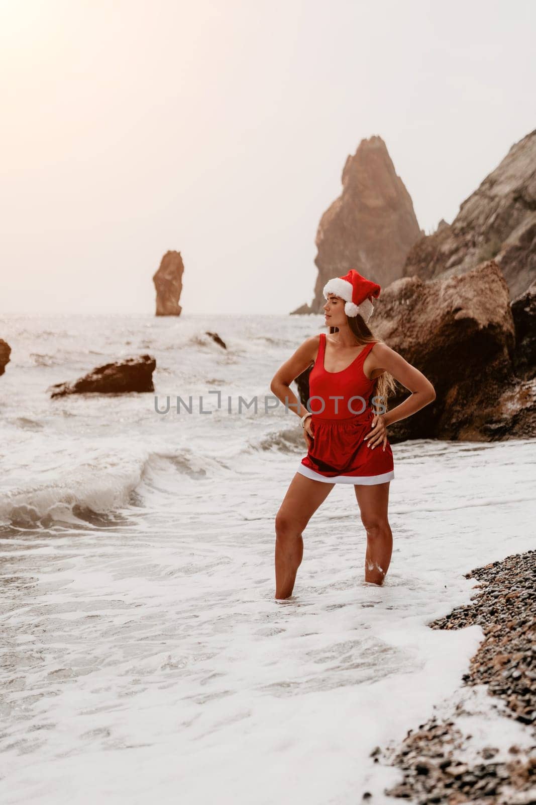 Woman travel sea. Young Happy woman in a long red dress posing on a beach near the sea on background of volcanic rocks, like in Iceland, sharing travel adventure journey