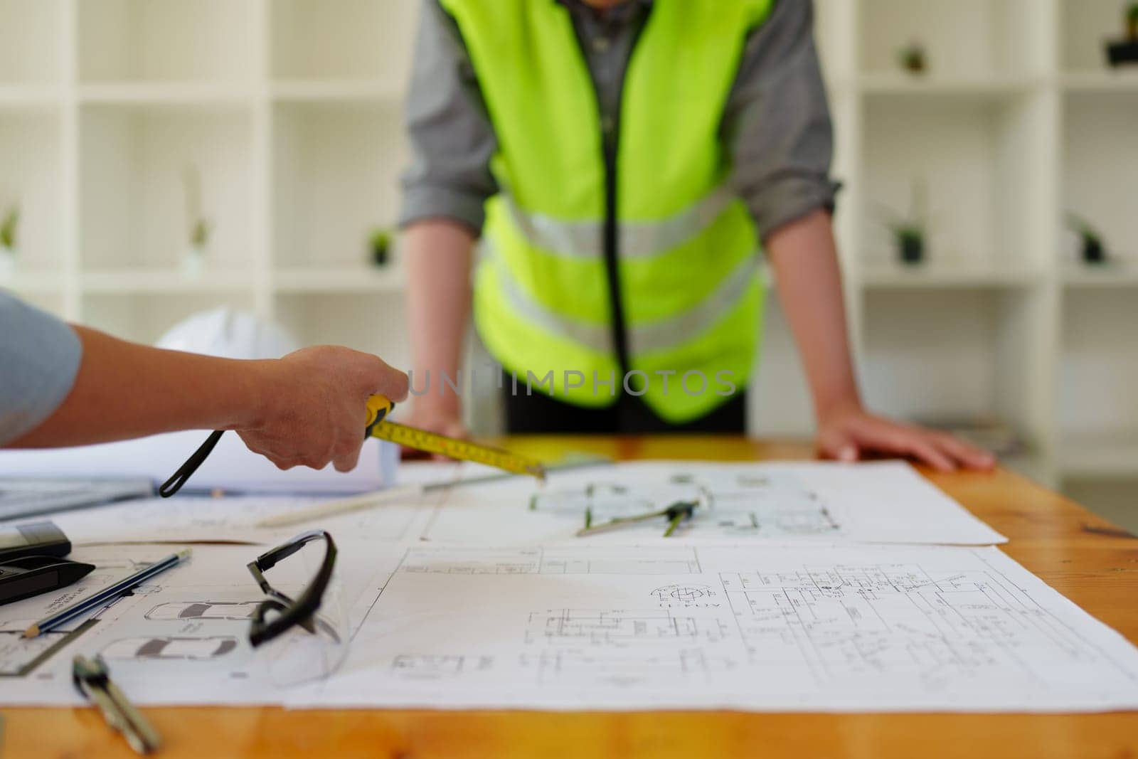 engineers discuss building on blueprint drawing, design building Project in office. by Manastrong