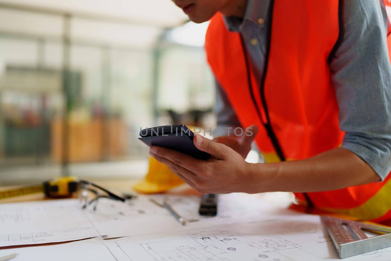 engineers discuss building on blueprint drawing using calculator. by Manastrong