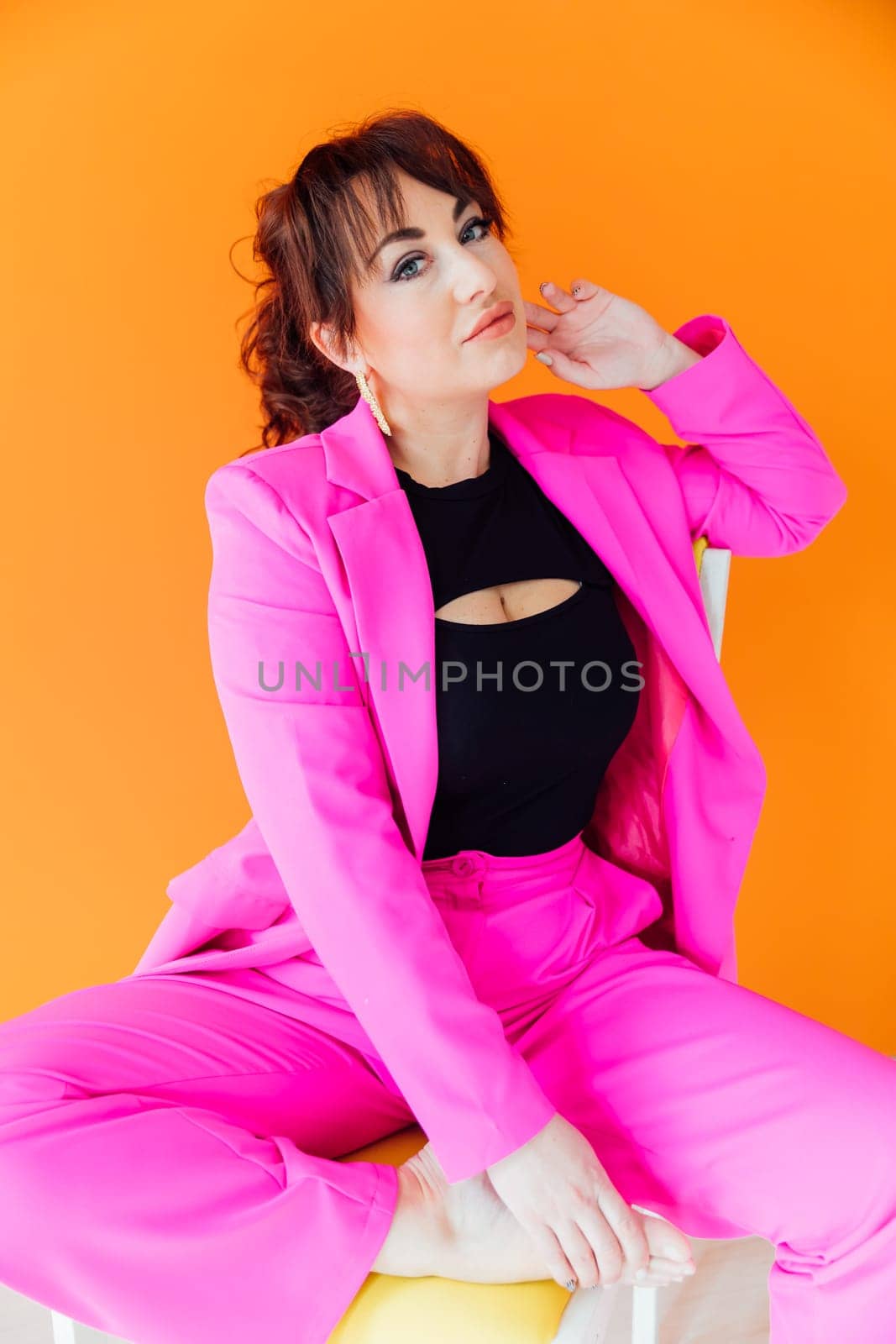 a woman in bright clothes on a chair on an orange background by Simakov