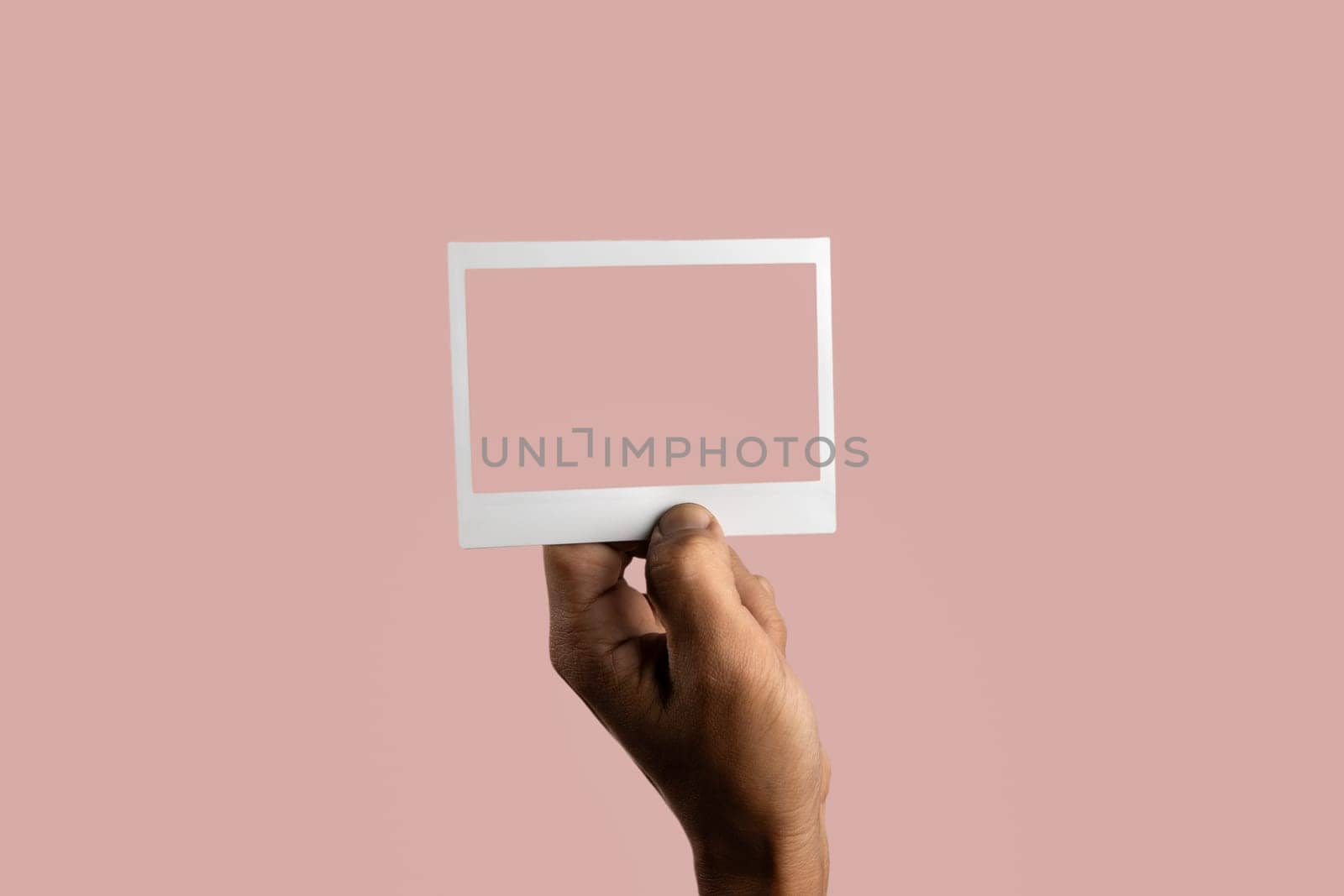 black male hand holding photo frame on isolated on light pink background by TropicalNinjaStudio