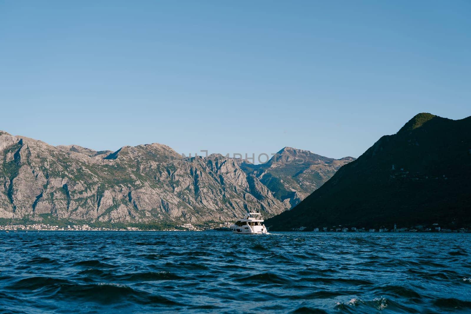Boat floats on the blue sea against the backdrop of a high mountain range. High quality photo