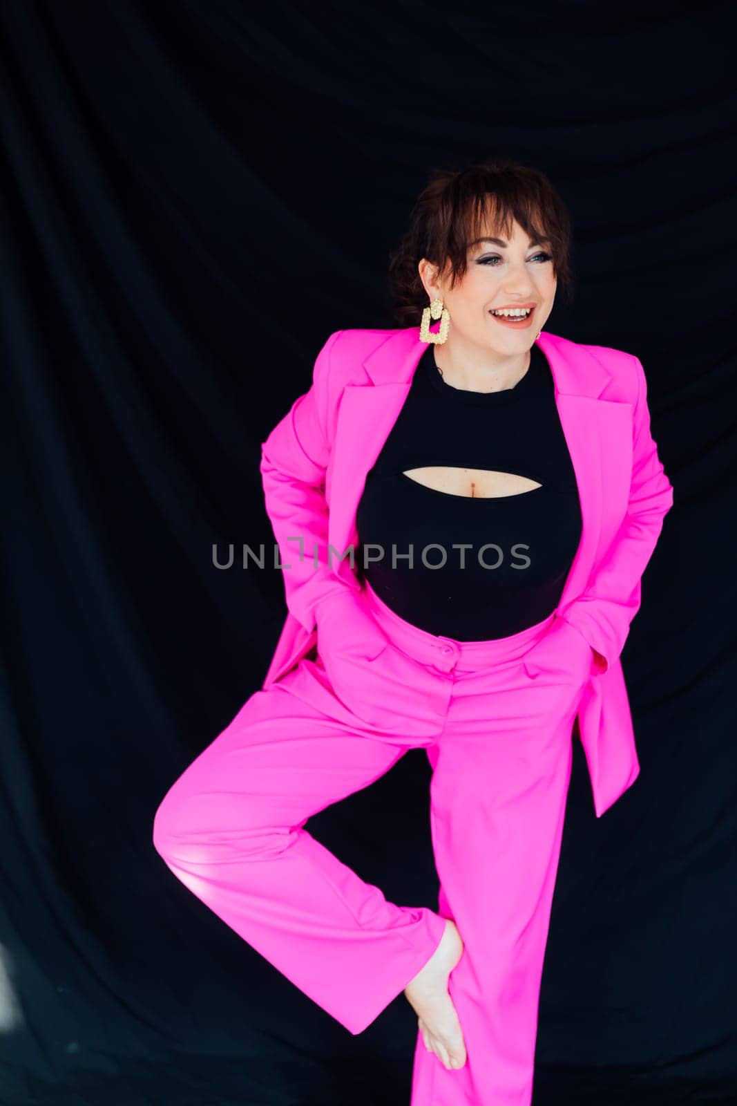 fashionable woman in bright clothes poses on a black background