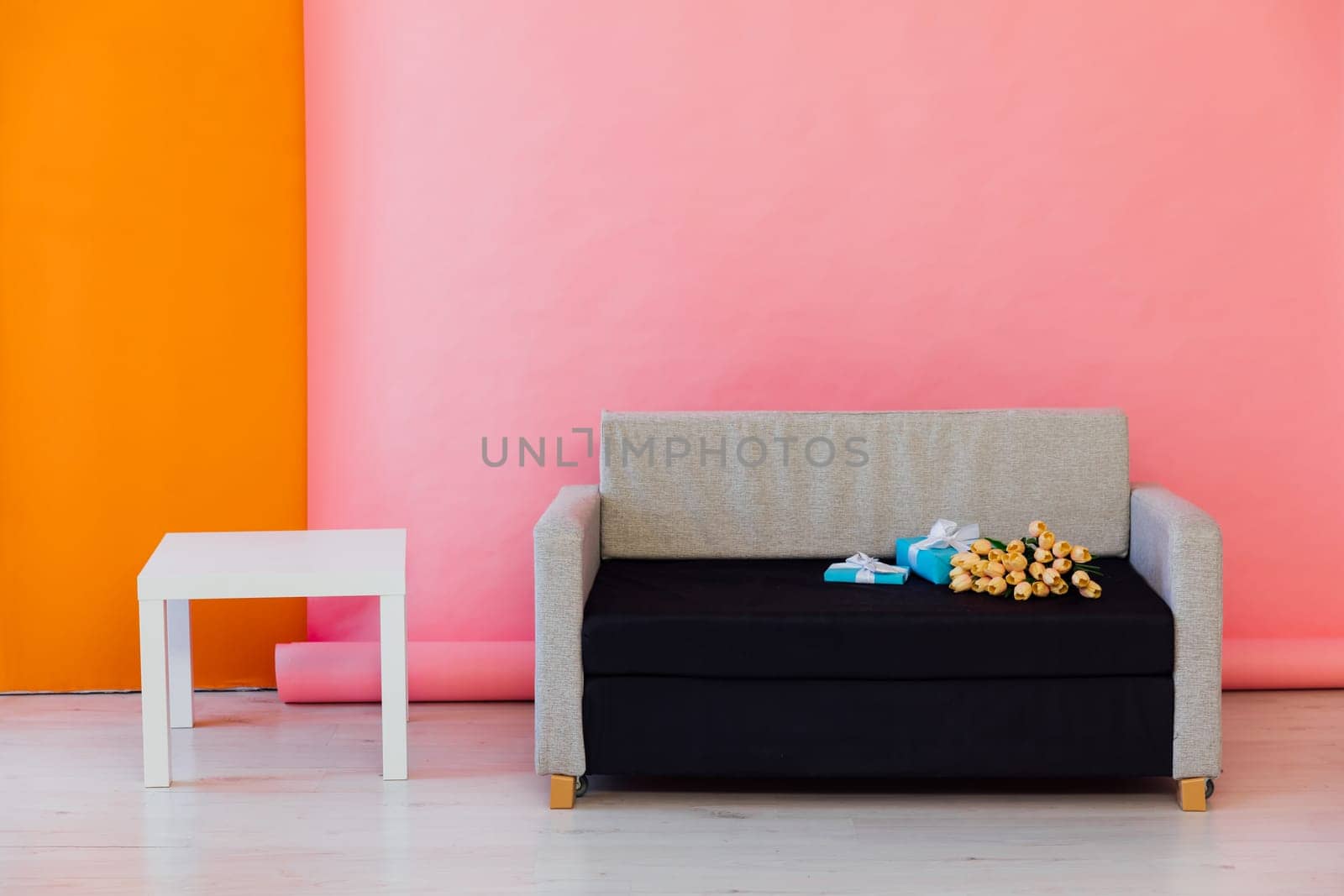 sofa with flowers and gifts coffee table on pink background interior in the room by Simakov