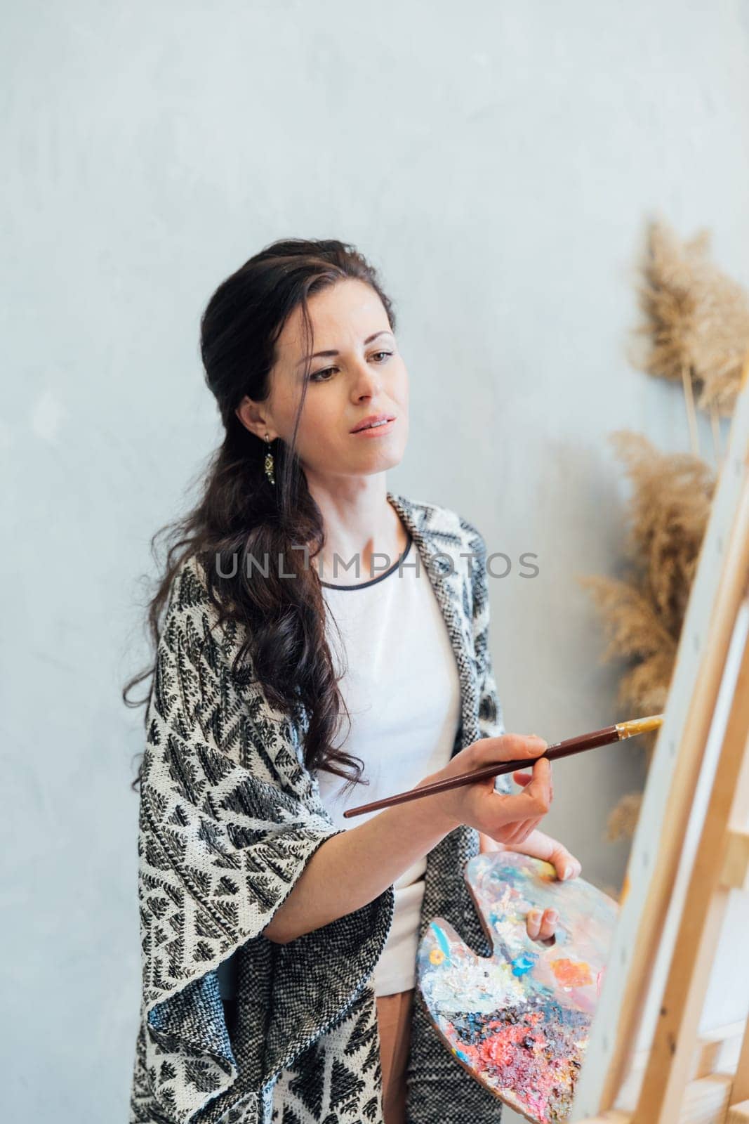 woman artist paints on white canvas at brown flowers by Simakov