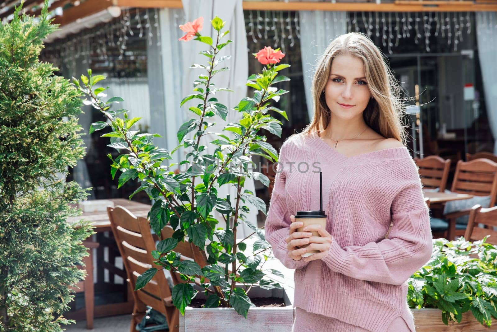 beautiful blonde woman on vacation outside with a glass of cocoa tea coffee