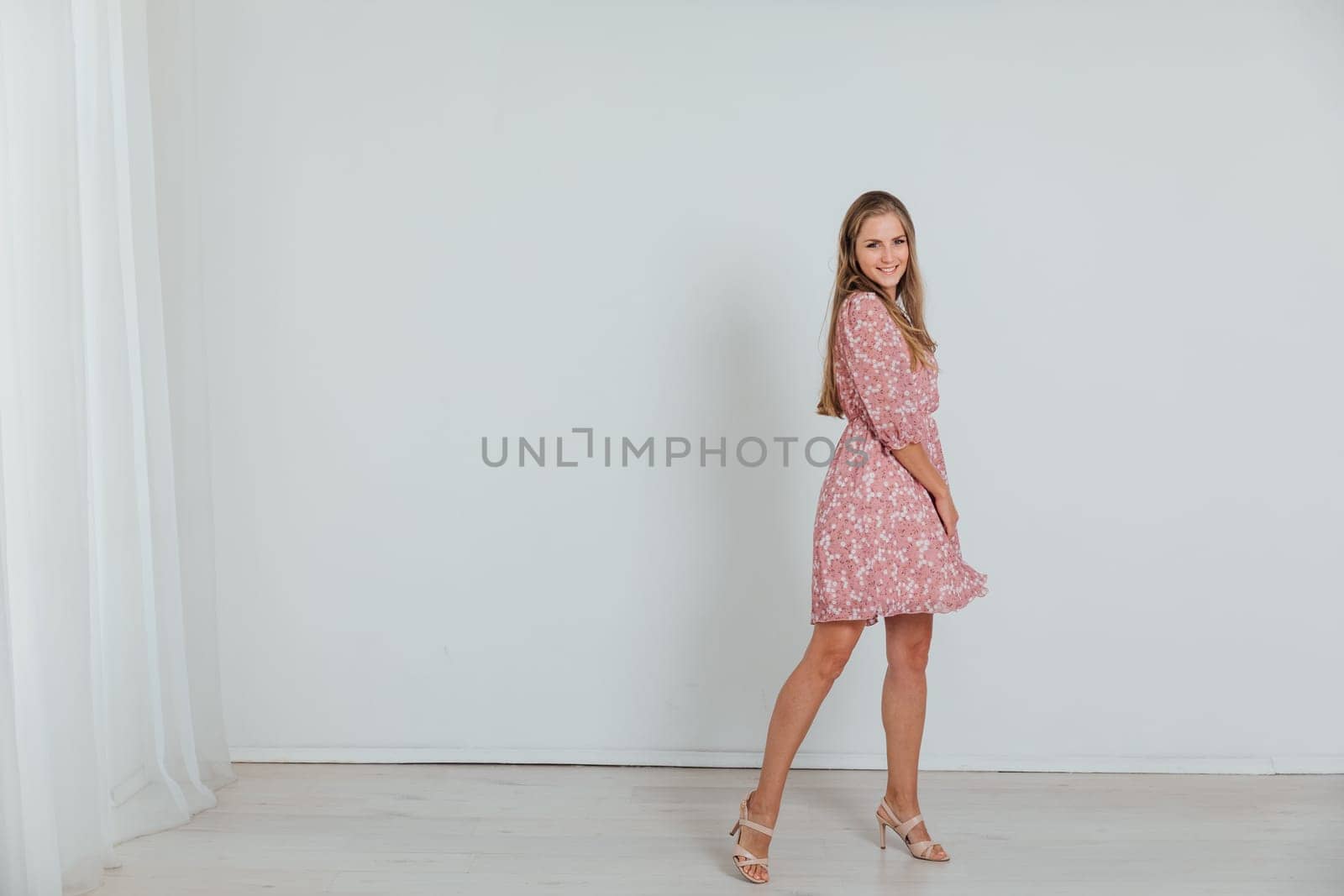 beautiful woman in a dress poses on a white background in a room