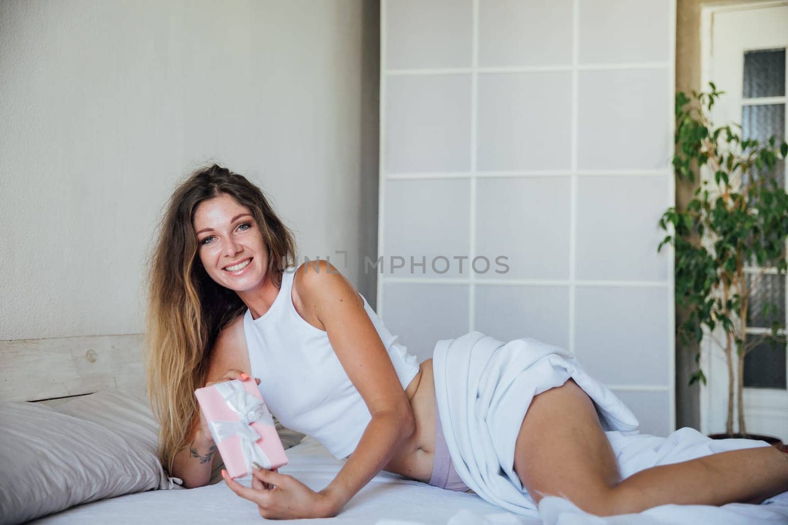 a woman with a gift in the morning in the bedroom on the bed