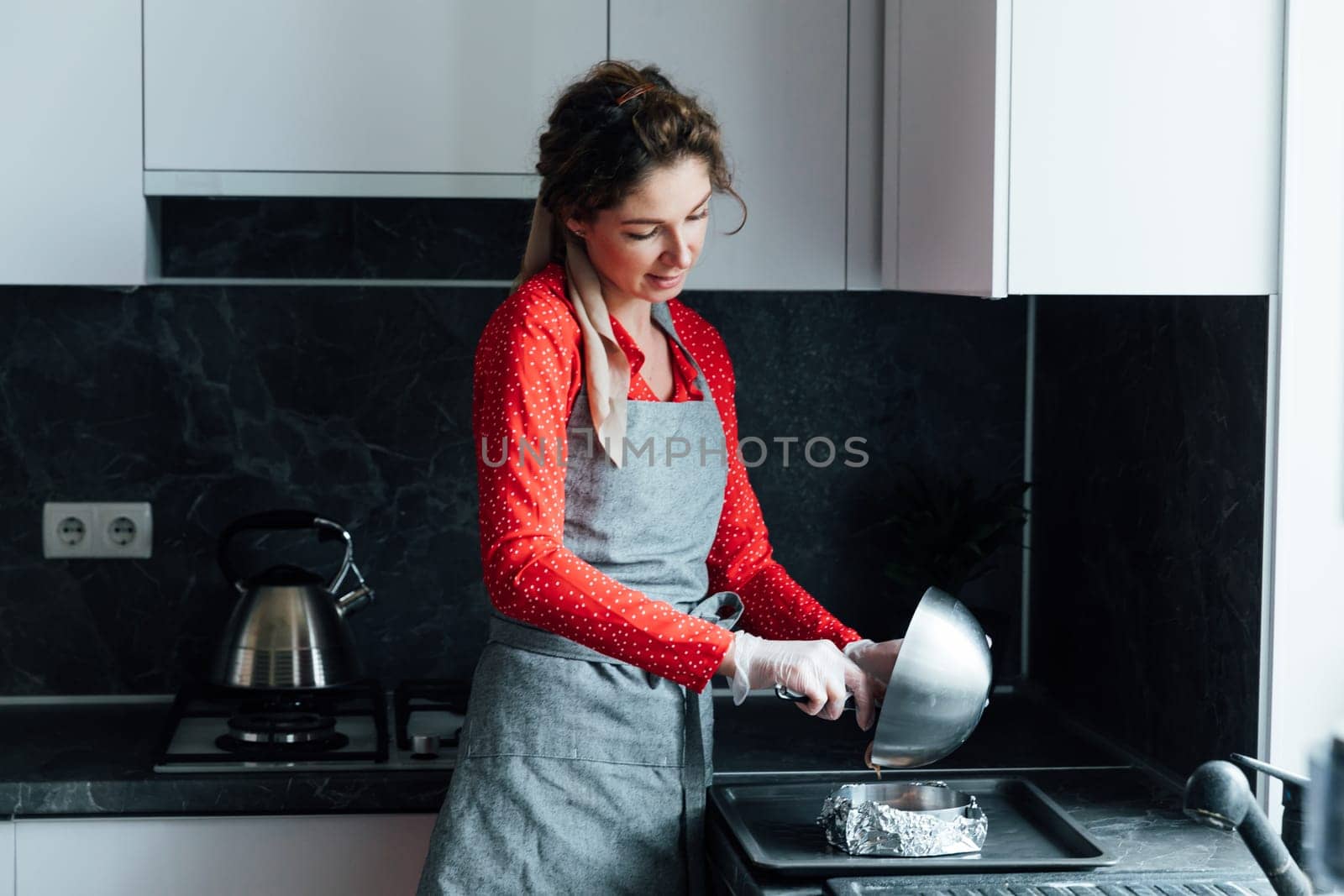 a housewife prepares food in the kitchen with gloves