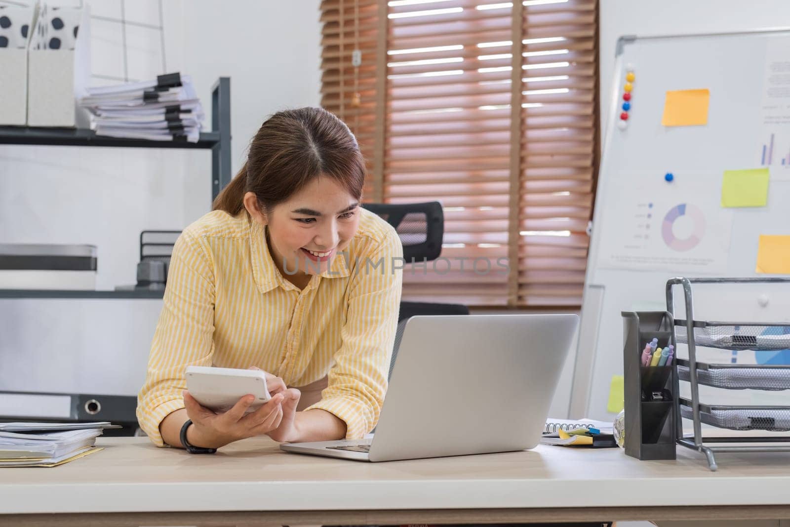 Close up Business woman using calculator and laptop for do math finance on wooden desk in office and business working background, tax, accounting, statistics and analytic research concept.