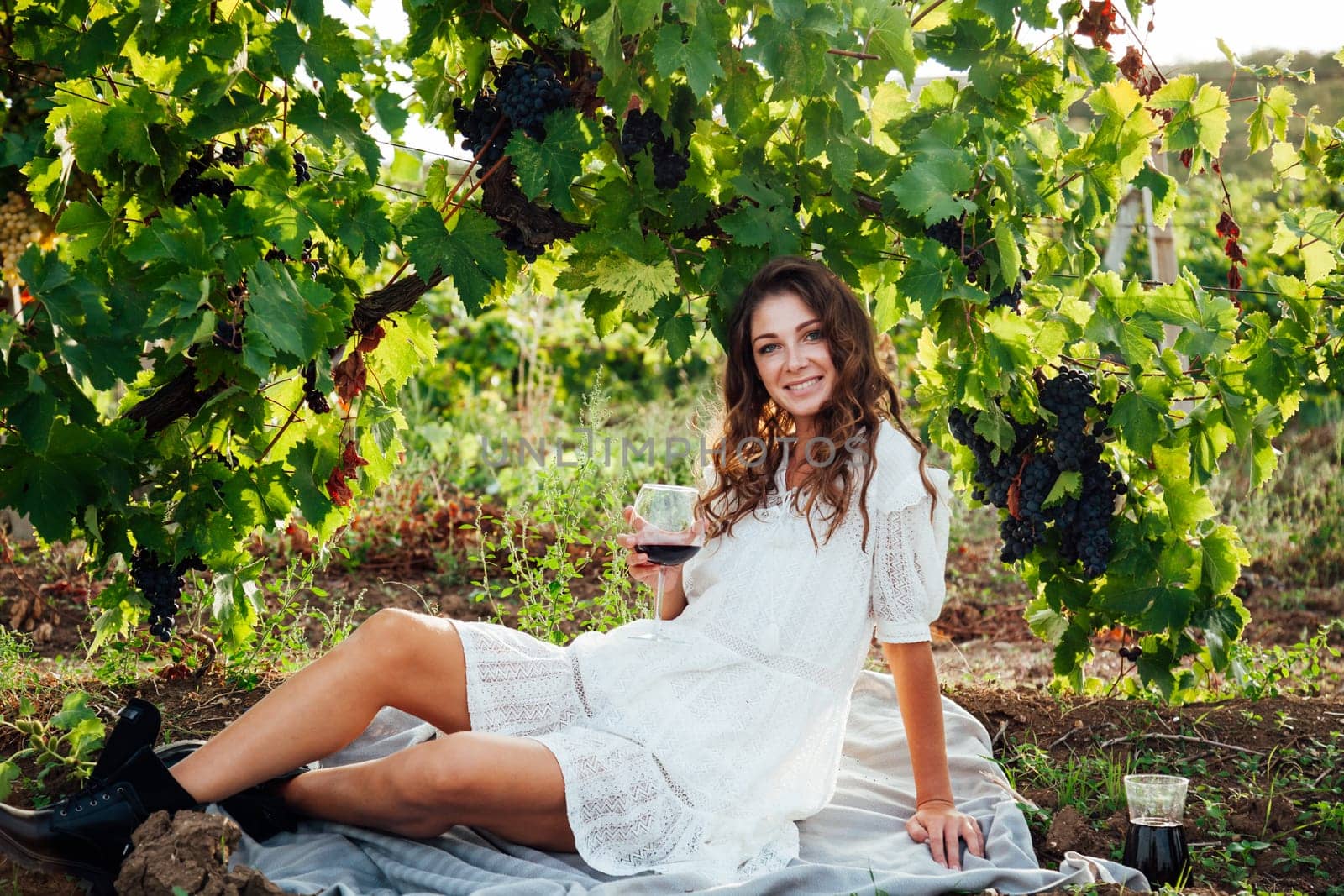 woman sitting by a grape with a glass of red wine