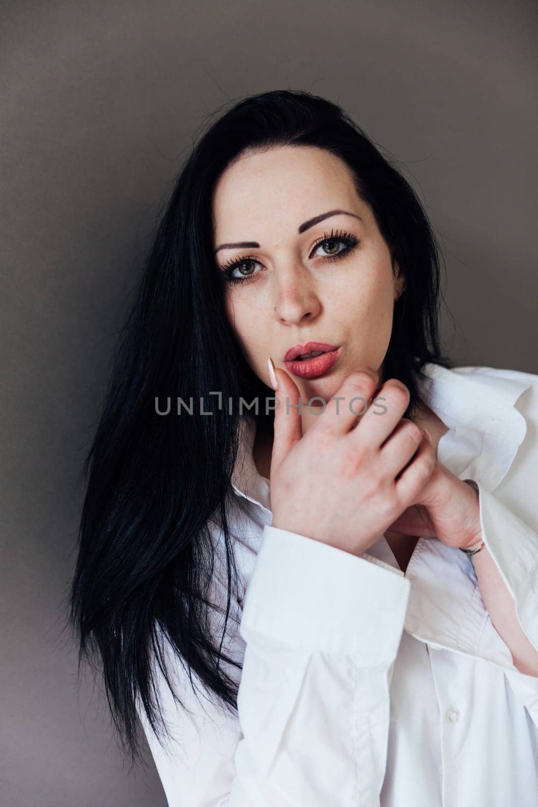 woman brunette adjusts lipstick lipstick on lips with her hand by Simakov