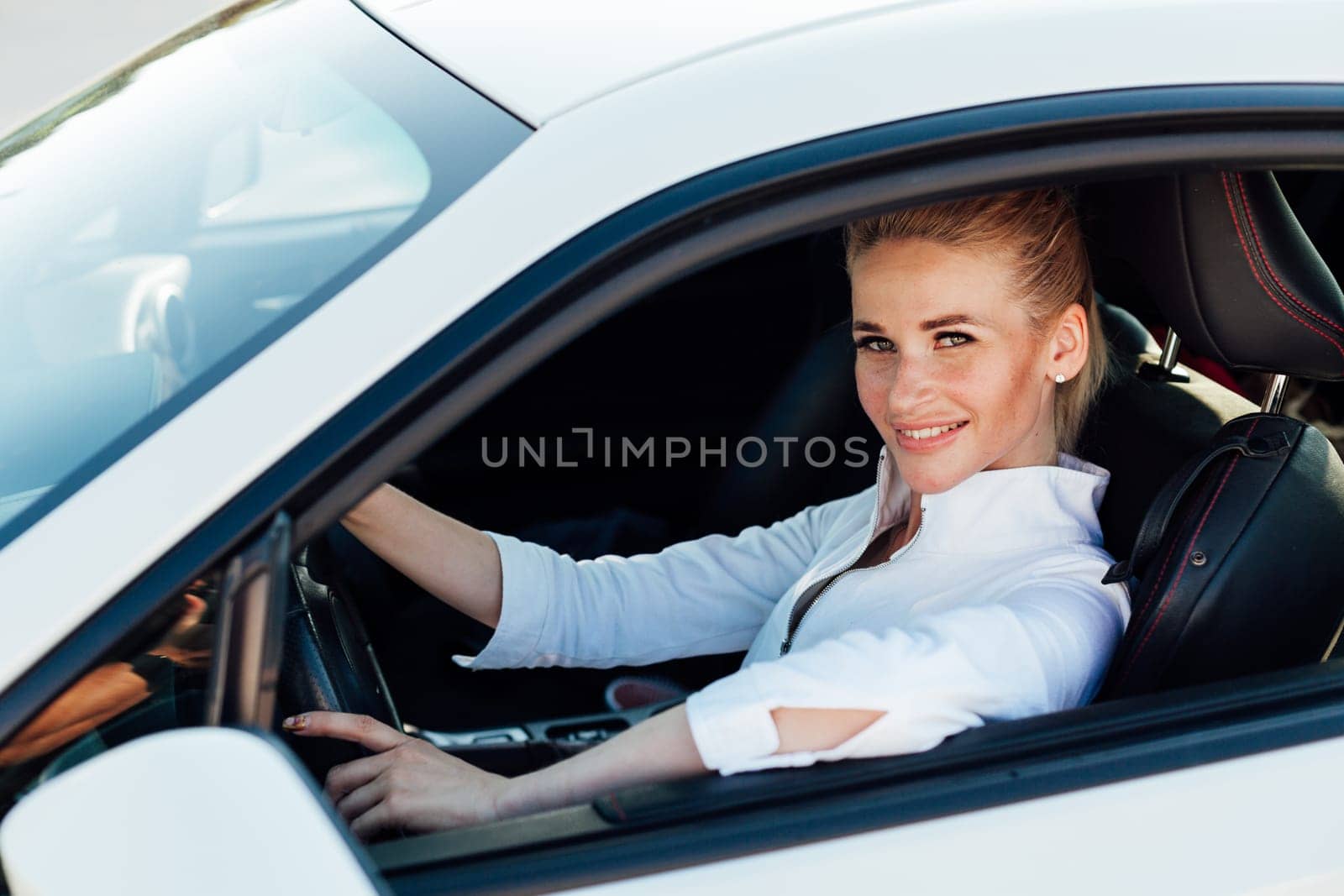 female driver behind the wheel of white car