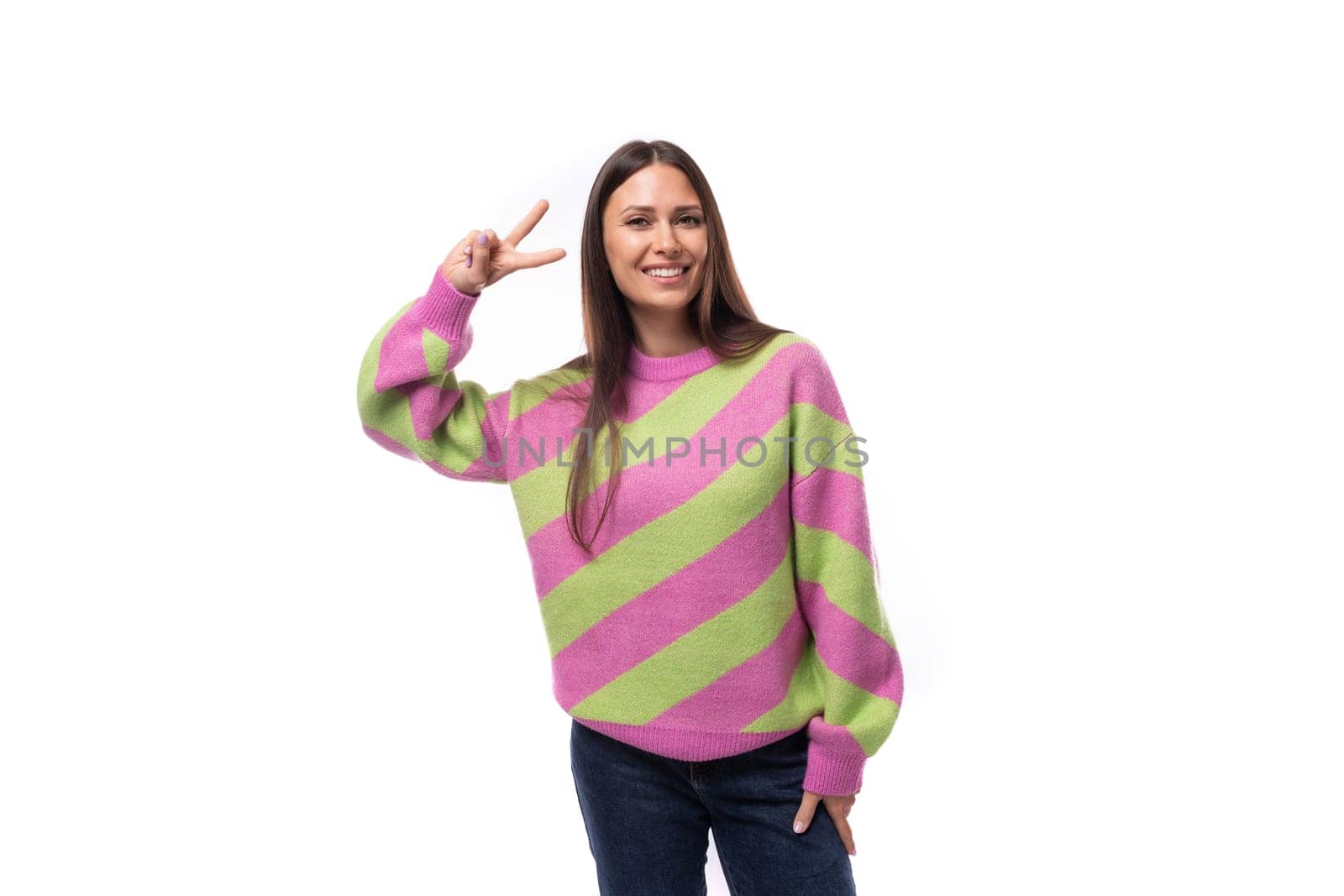 young happy caucasian woman with straight black hair is dressed in a stylish striped pink pullover.