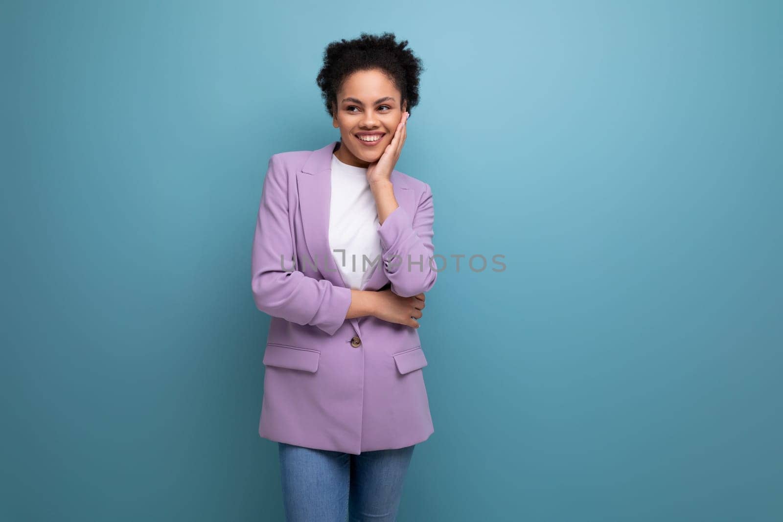 young pretty latin secretary woman with wavy hair dressed in purple jacket on studio background with copy space.