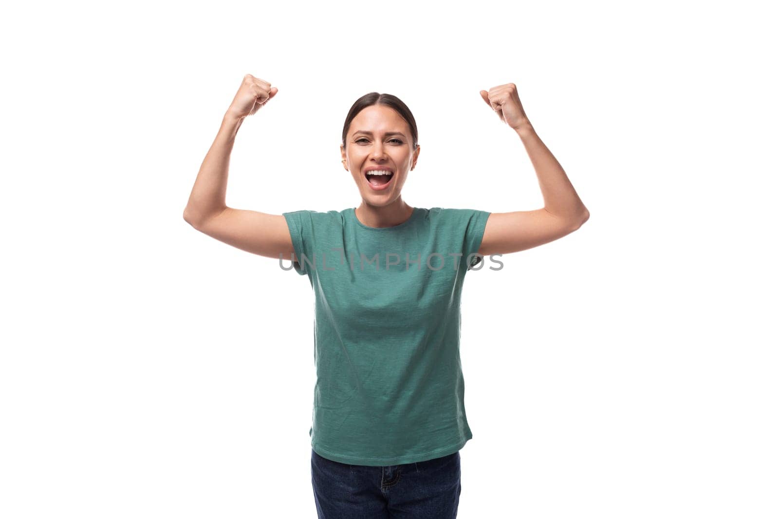 well-groomed slender young brunette woman dressed in a green T-shirt is emotionally aroused and raised her hands.