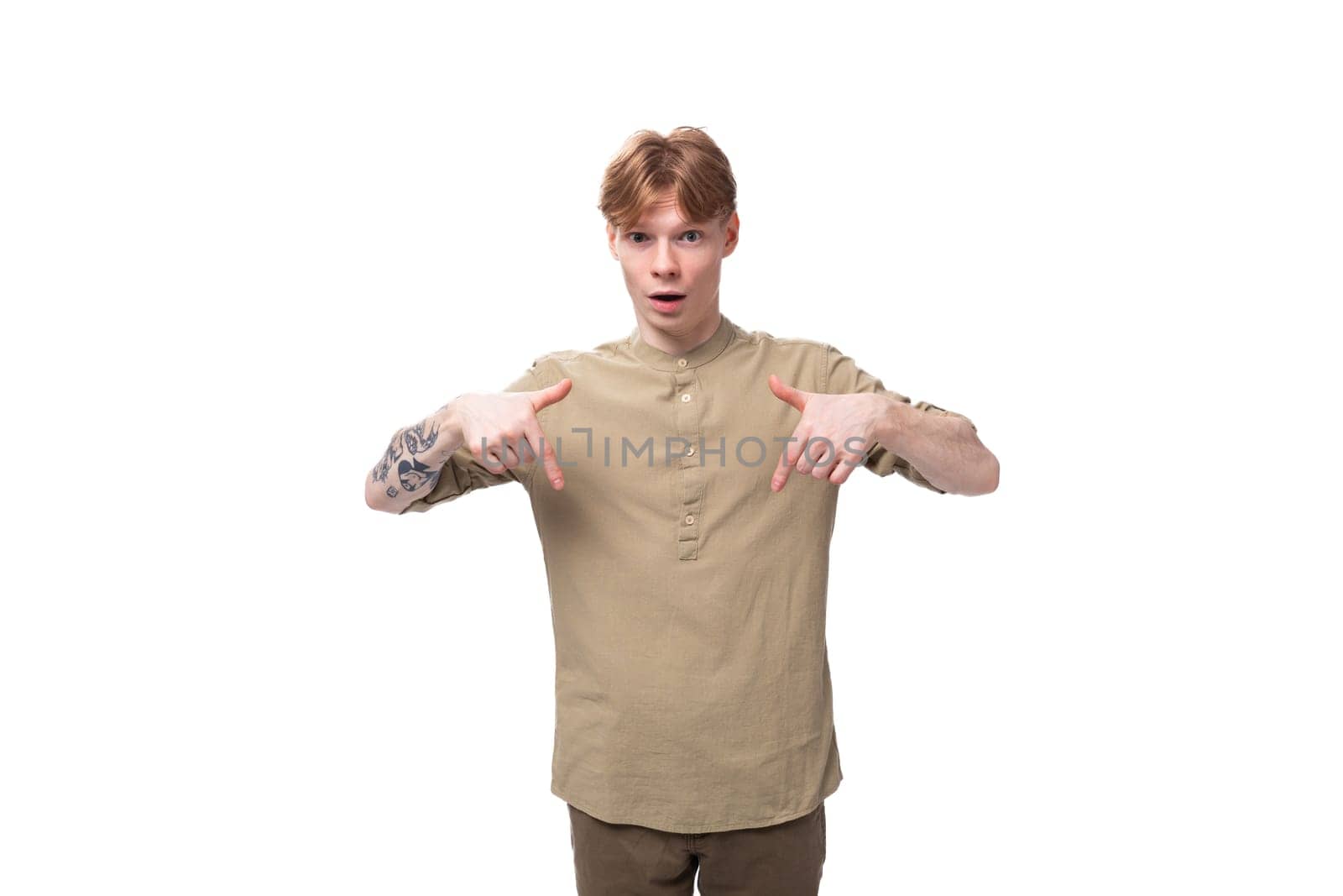 young surprised red-haired man in a beige shirt on a white background.