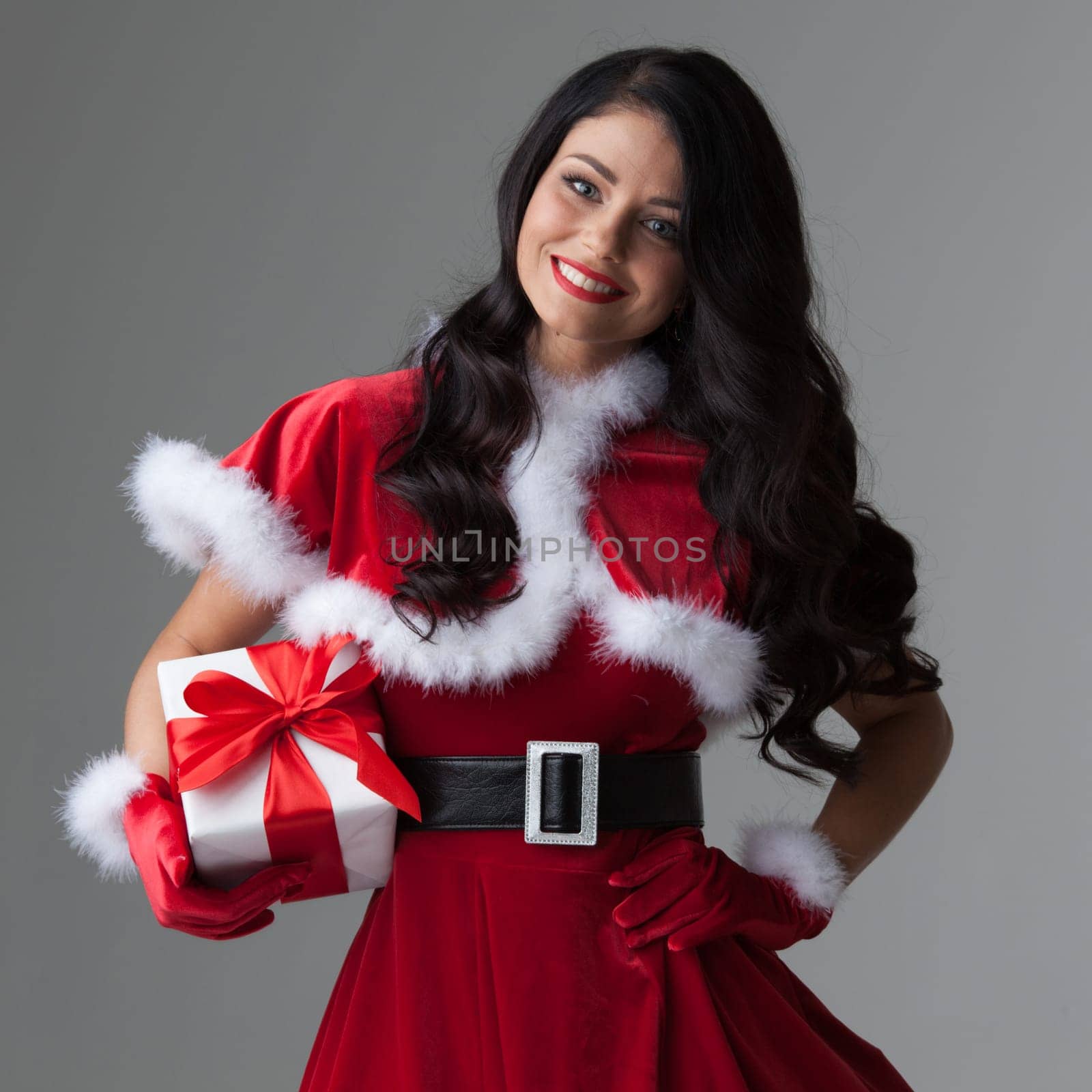 Woman in red Santa Claus outfit holding christmas gift box