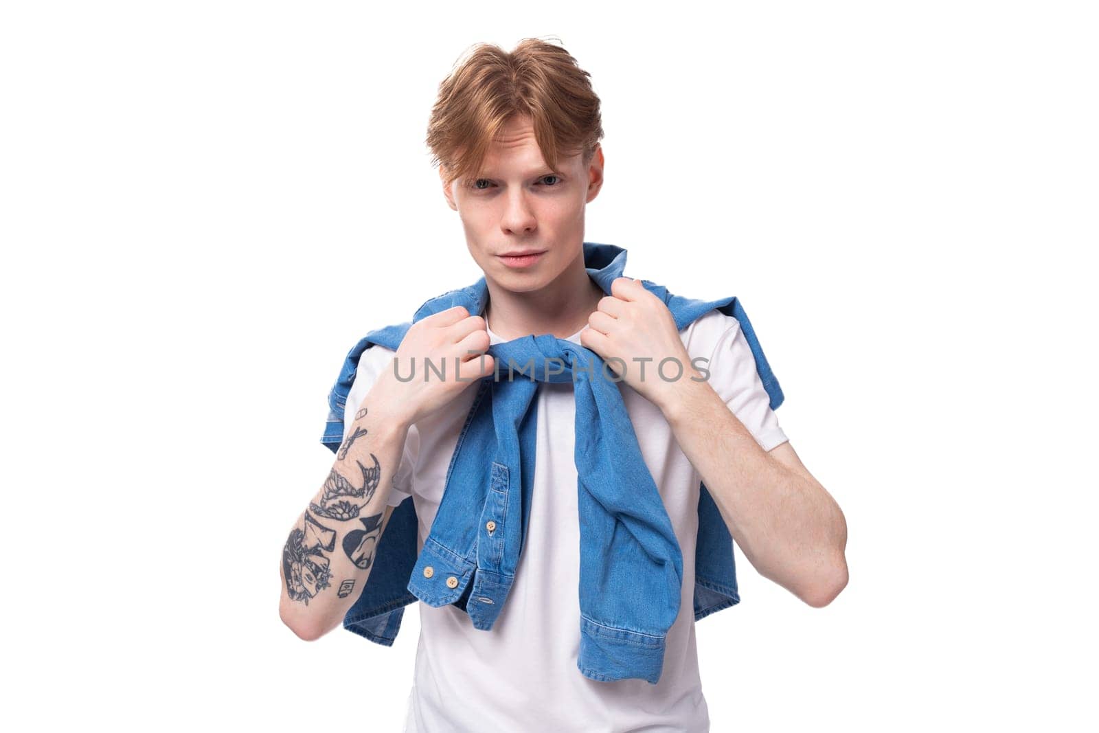 young red-haired guy with a cool hairstyle is dressed in a blue denim shirt on a white background.