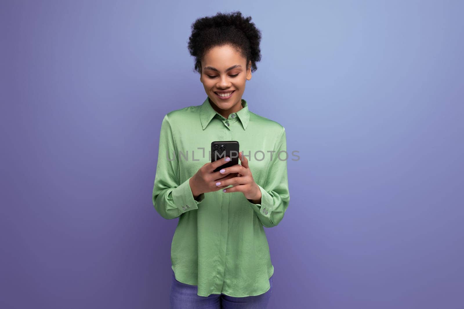 young positive latin woman dressed in a green shirt chatting on a smartphone.