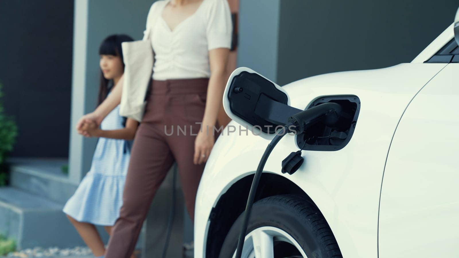 Progressive lifestyle of mother and daughter with EV car and charging station. by biancoblue