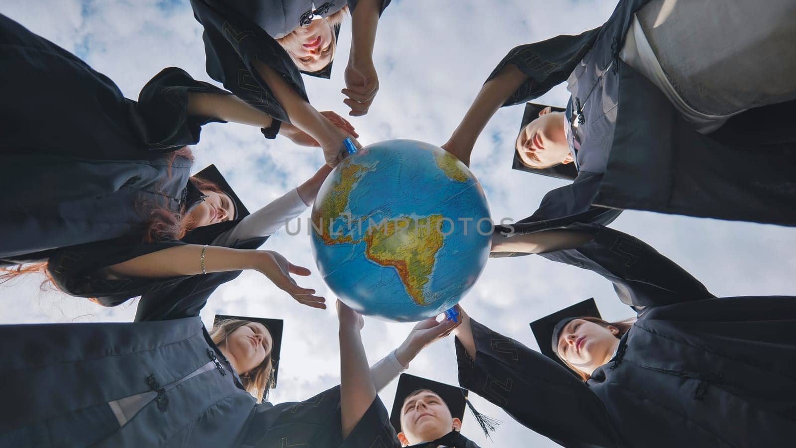 Graduating students spin a geographical globe of the world