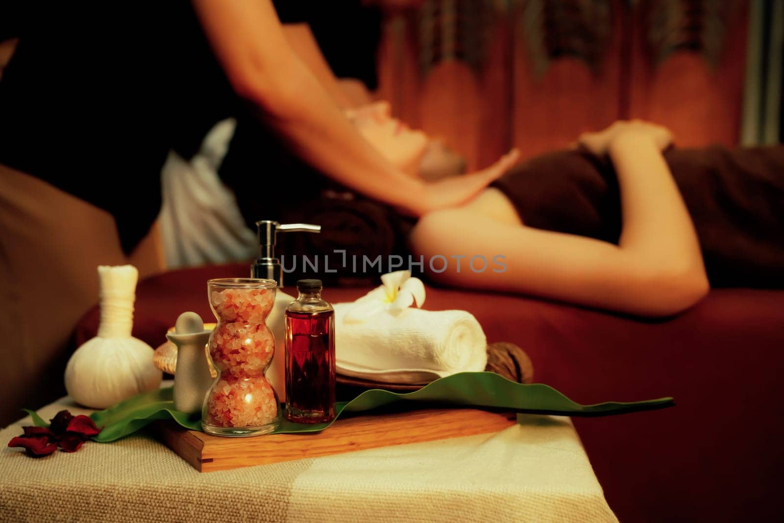 Aromatherapy massage ambiance or spa salon composition setup with focus decor candles and spa accessories on blur couple enjoying blissful aroma spa massage in resort or hotel background. Quiescent