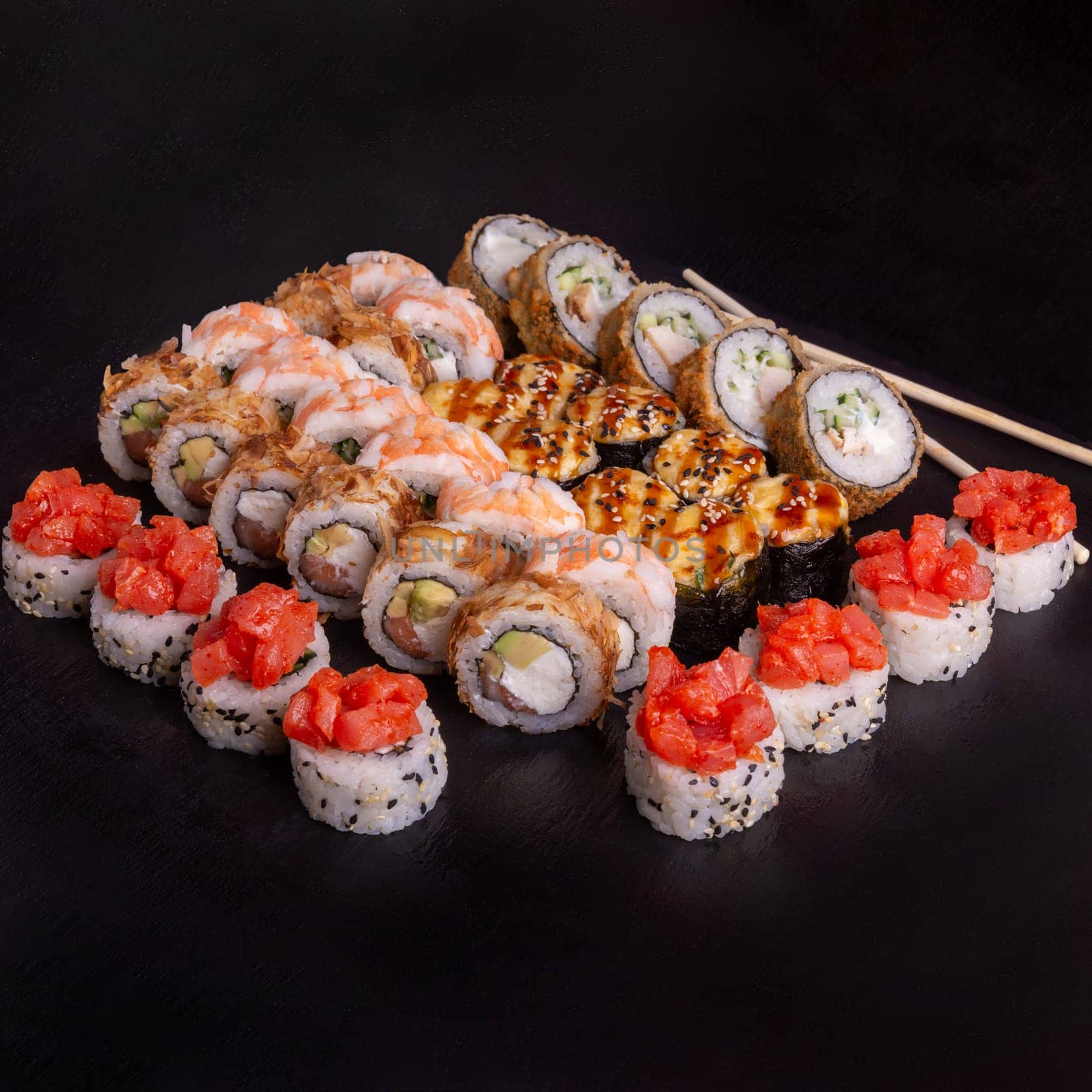 Sushi set on slate plate isolated on black background. 5 types of rolls in one set.