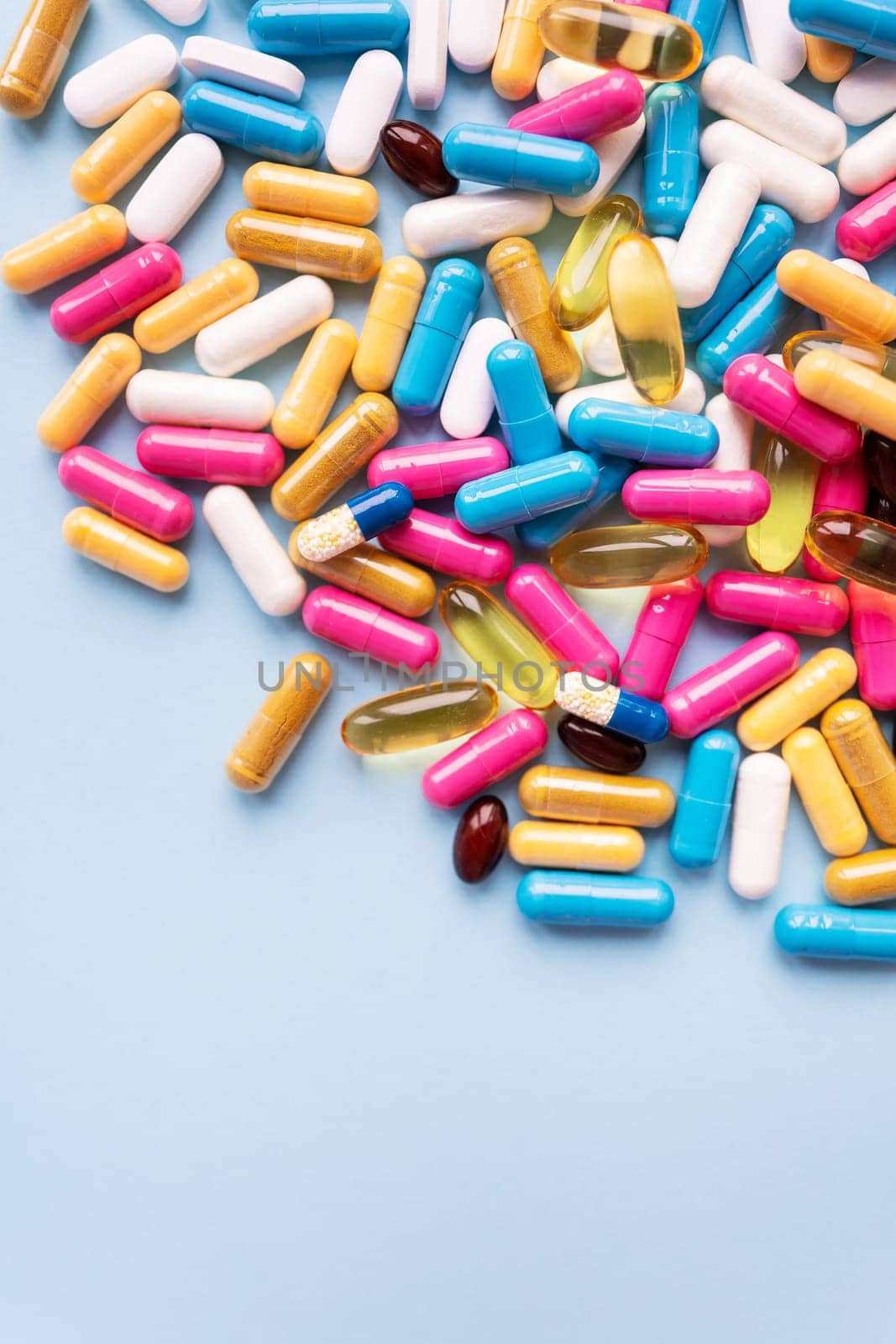 Lots of colorful pills and capsules for different symptoms on a blue background. Health and medicine concept