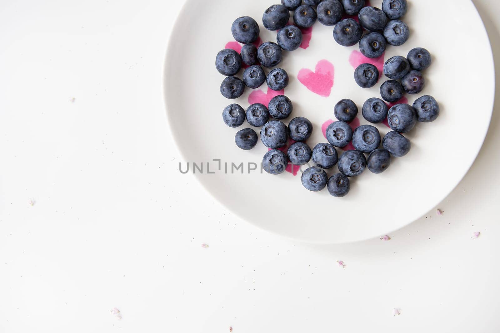 Delicious blueberries lie on a plate with a heart inside. Delicious and healthy food. Place for an inscription