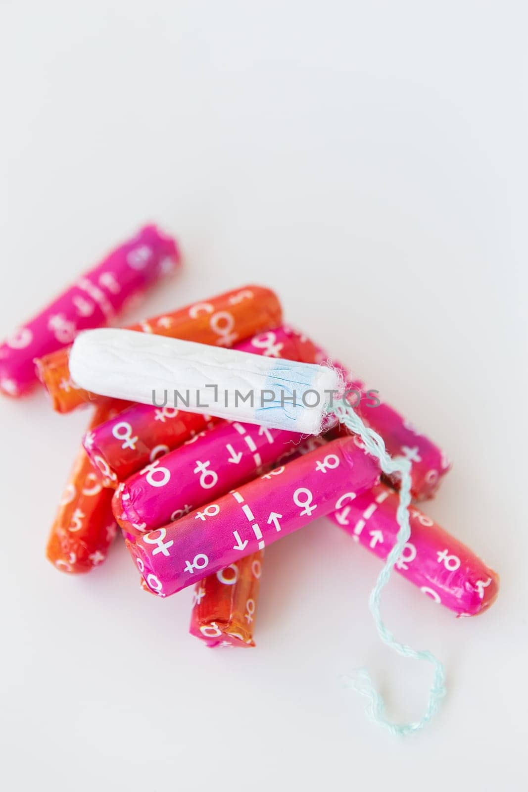 Pink and orange tampons and one opened tampon. Hygiene and health concept. Place for an inscription, vertical photo