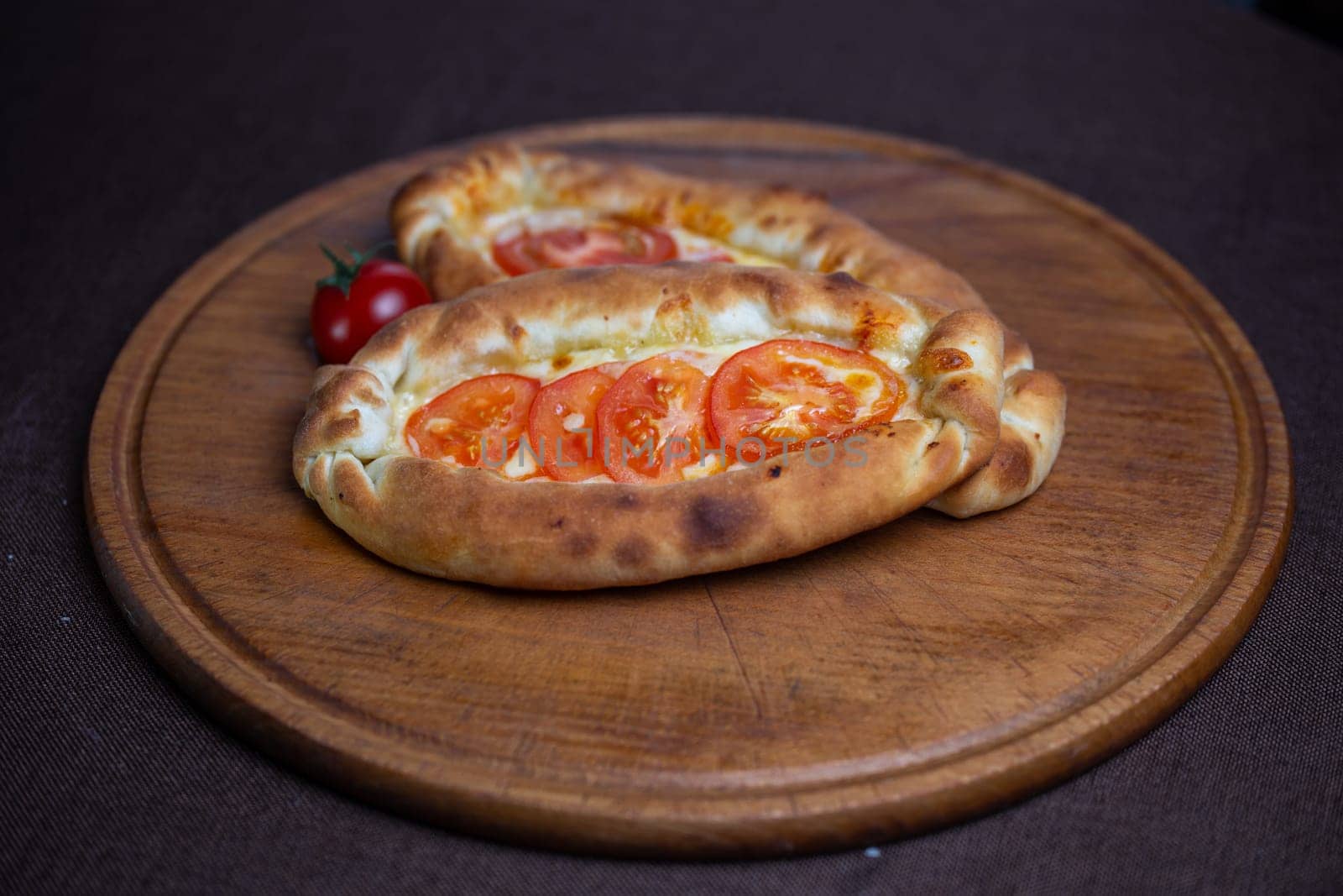 khachapuri recipe with tomatoes. khachapuri on a wooden plate by Pukhovskiy