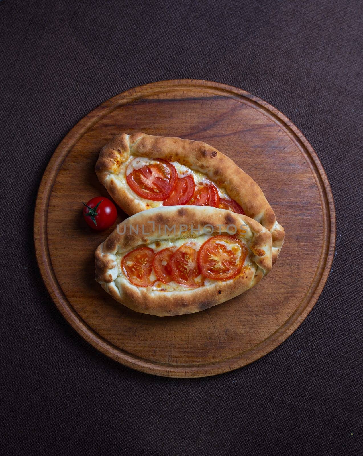 top view of khachapuri recipe with tomatoes. khachapuri on a wooden plate.