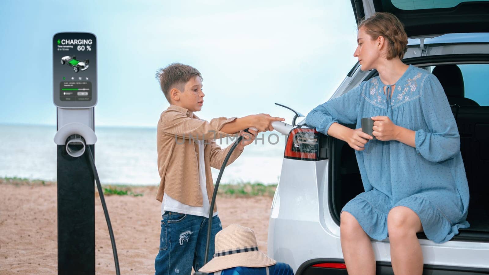 Family road trip vacation traveling by the beach with electric car, mother and son recharge EV car with green and clean energy. Family natural travel with eco-friendly car. Perpetual