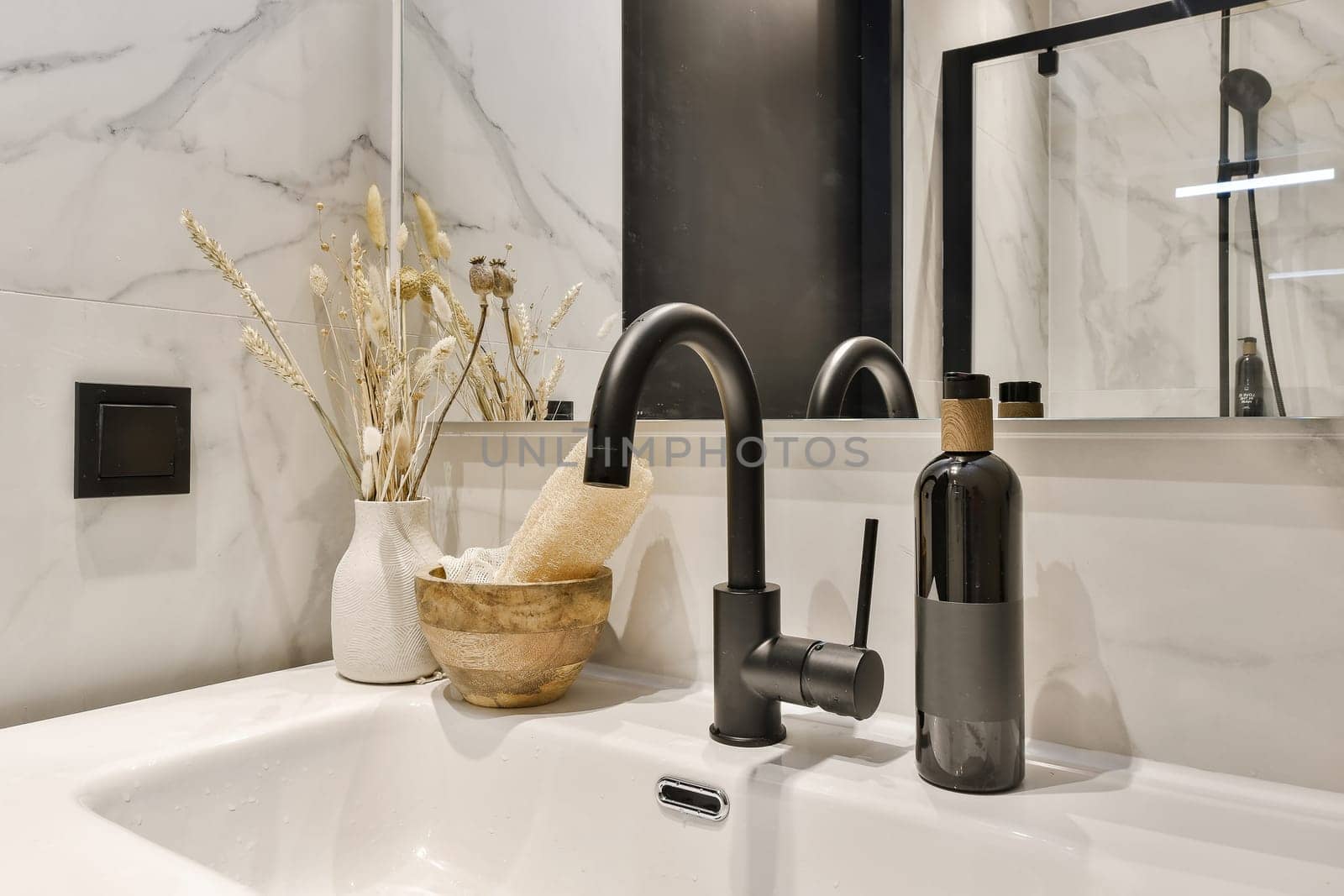 a bathroom sink with some flowers in the bowl and a mirror on the wall behind it is a black fae