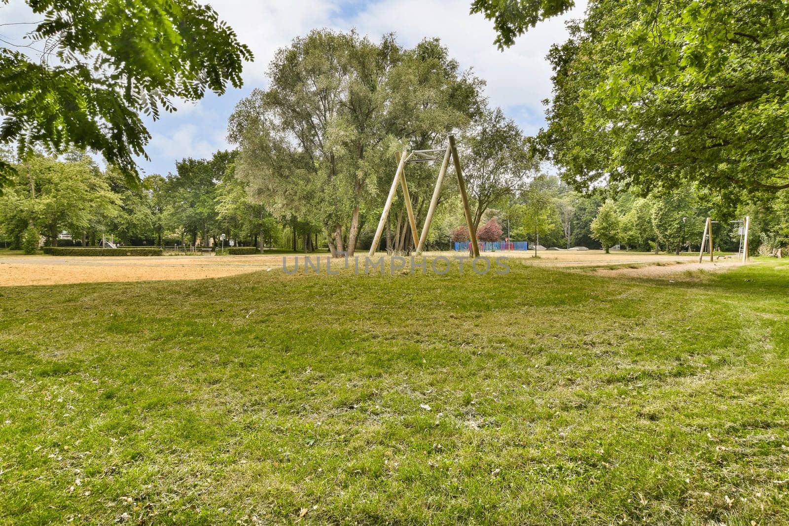 a swing set in a park with grass and trees by casamedia