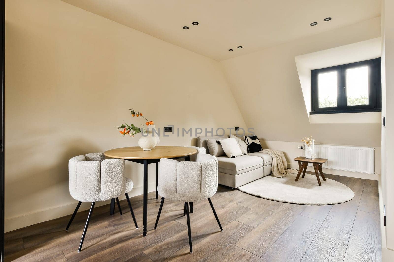 a living room with two chairs and a round table in the middle of the room, there is an open door leading to the