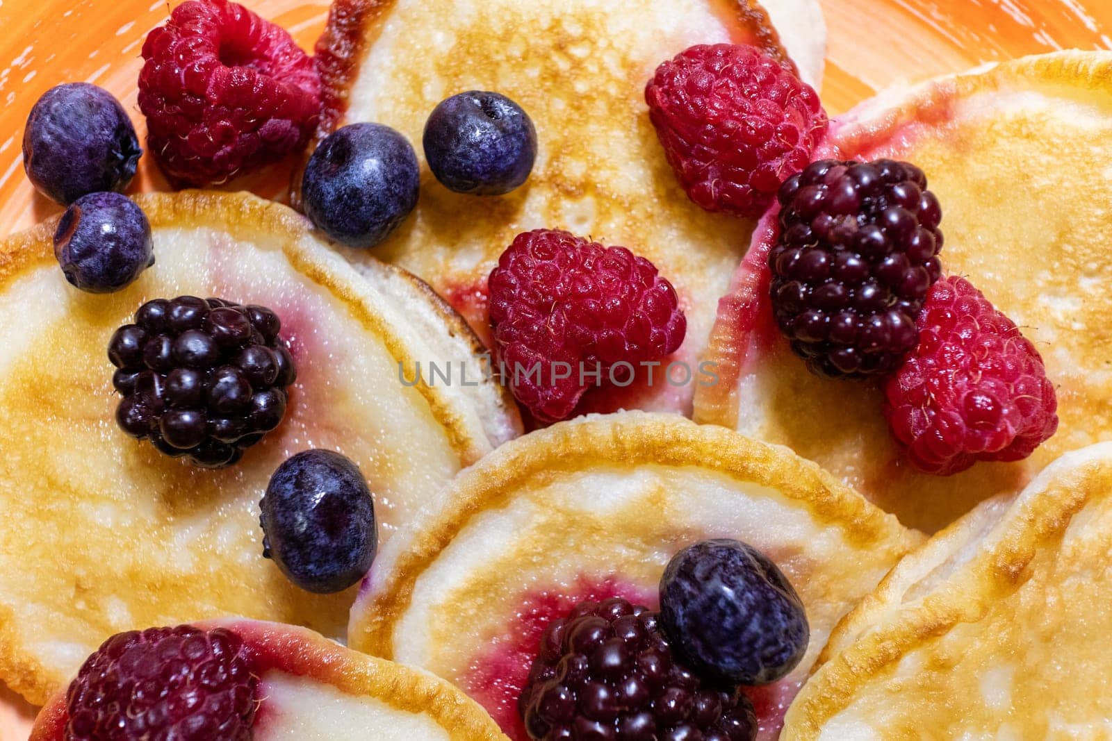 Close-up delicious pancakes, with fresh blueberries, raspberries and blackberries, the background of a delicious dessert