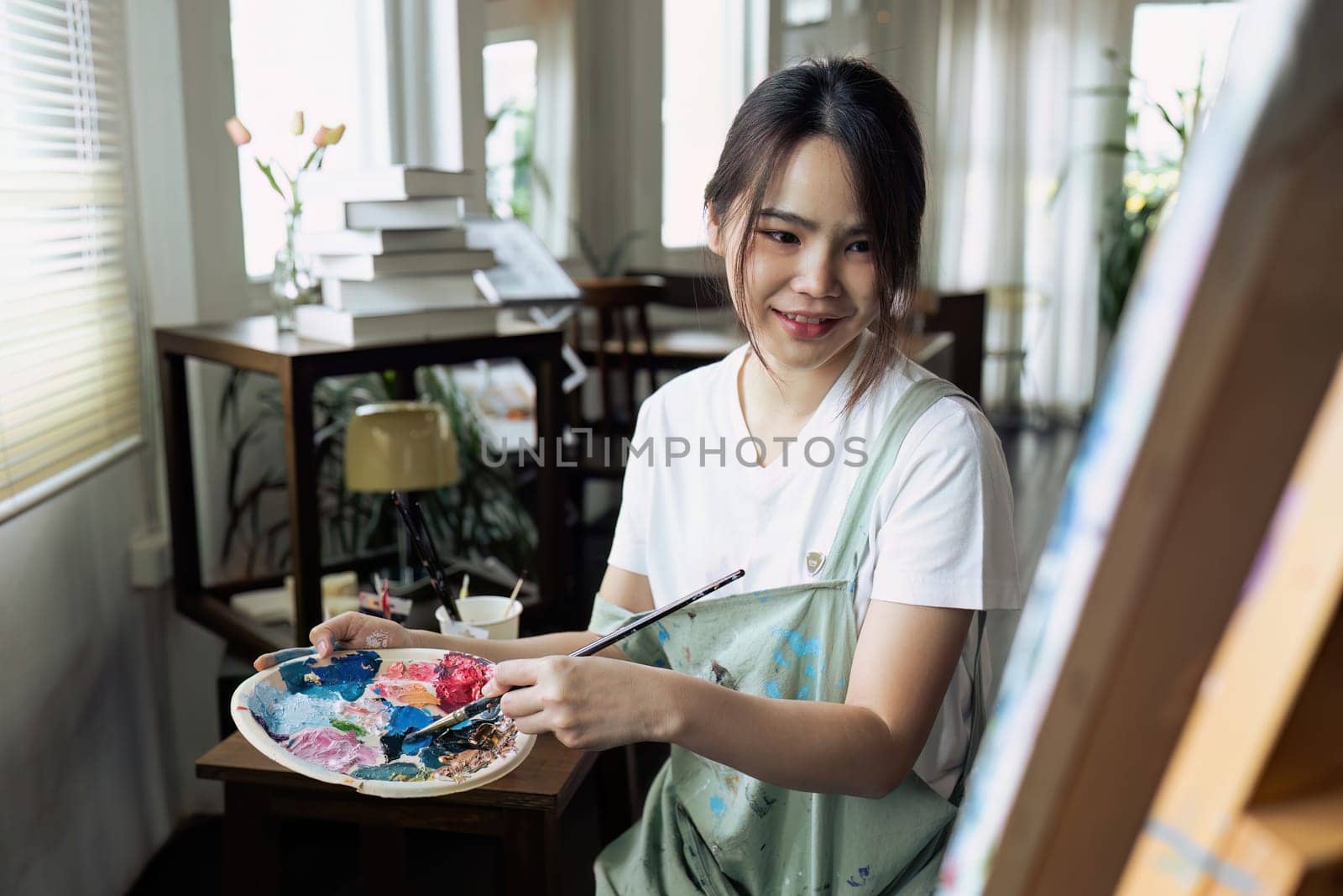 Female artist hold color palette and paintbrush for painting during hobby workshop by itchaznong