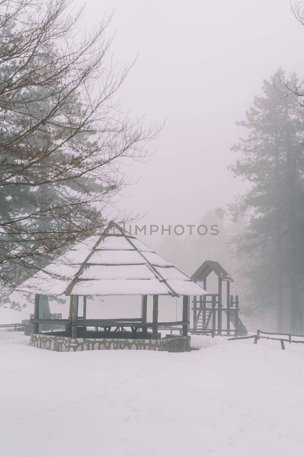 Snow-covered round gazebo in a winter foggy park. High quality photo