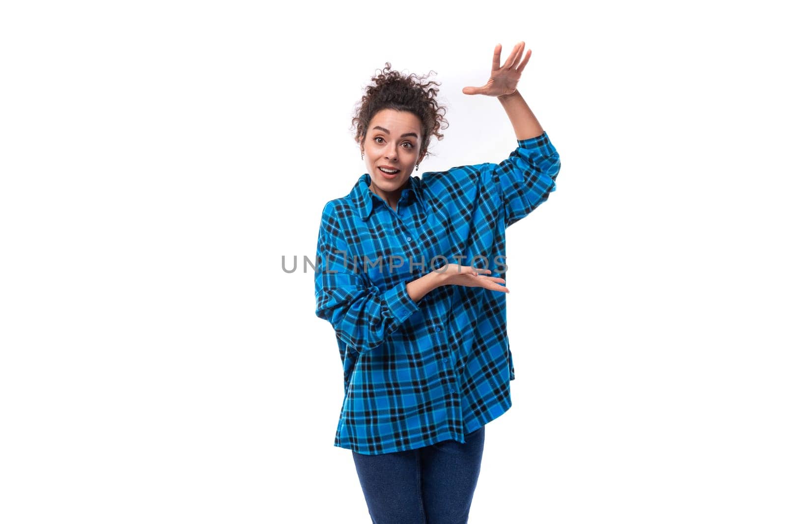a young beautiful European woman with curly hair is dressed in a blue checkered shirt and actively gesticulates. advertising concept.