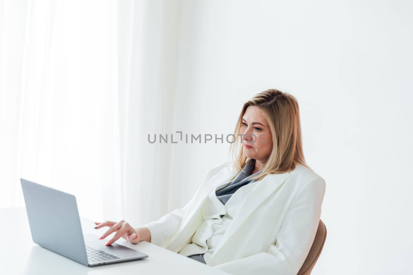 40s mid age European business woman CEO using laptop application for work sitting at table workspace in office. Smiling Latin Hispanic mature adult professional businesswoman using pc digital computer