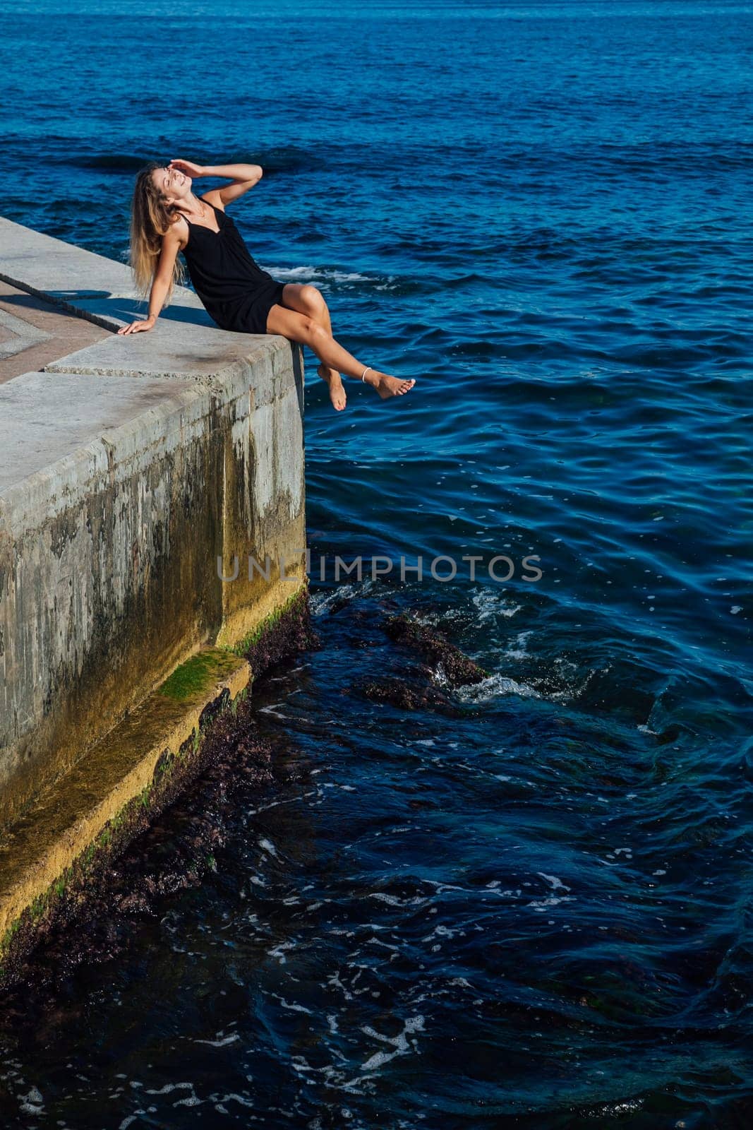 slender woman in black summer dress on the seashore