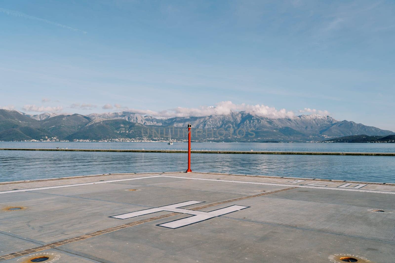 Helipad on the pier with a signal beacon by the sea against the backdrop of the mountains. High quality photo