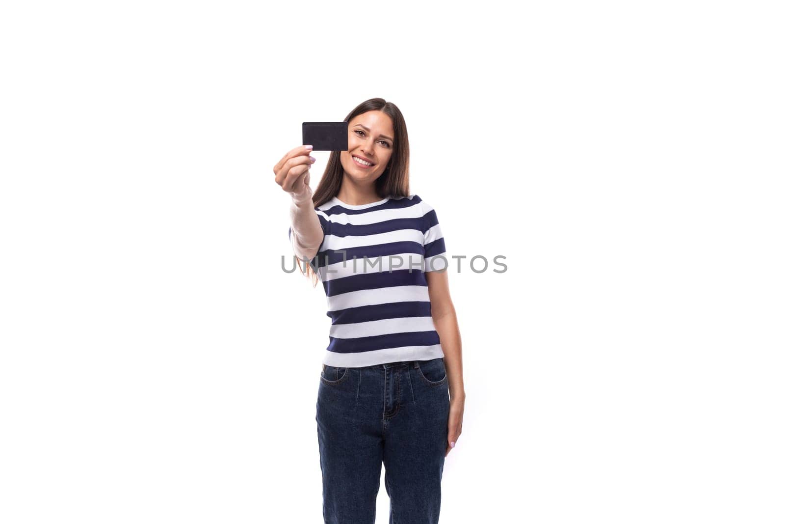 charming young european woman with black straight hair in a striped black and white t-shirt and jeans enjoys online payments using credit card details.