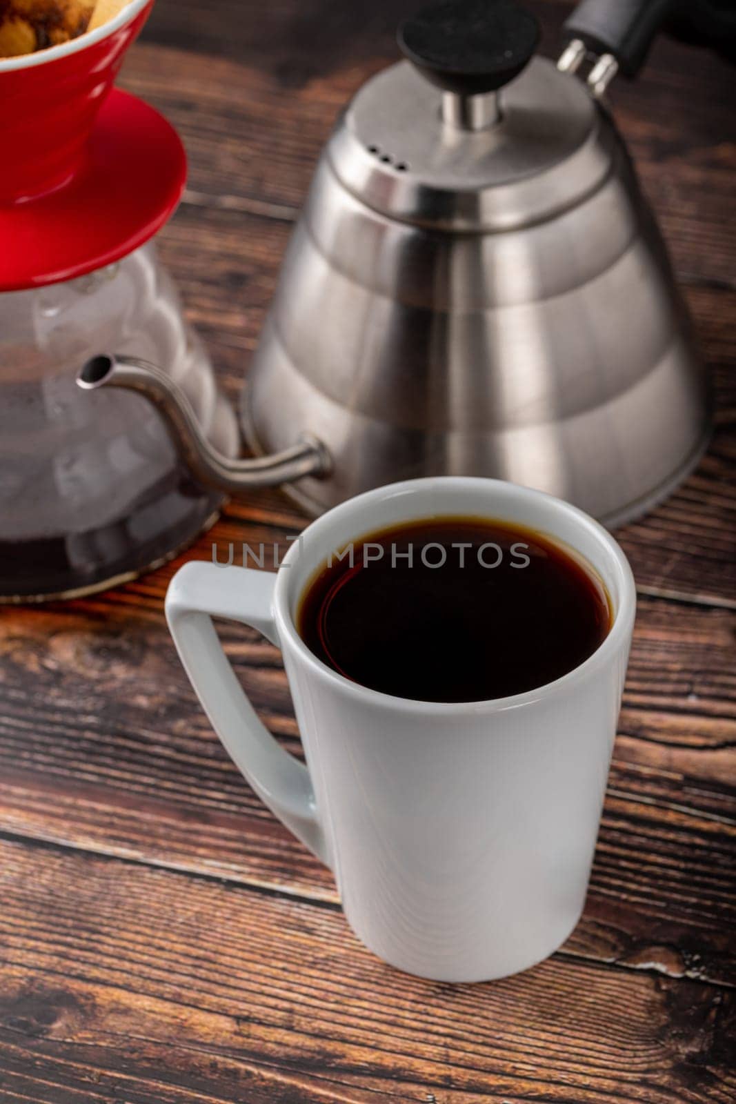 A cup of coffee and third generation pour over coffee brewing equipment on stone floor