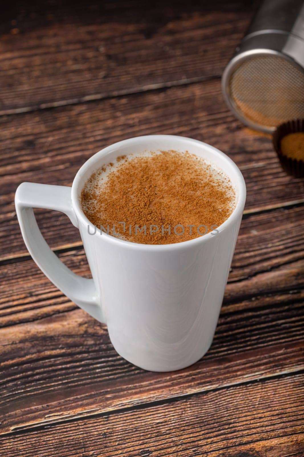 Cinnamon sprinkled salep in a white cup on wooden table by Sonat