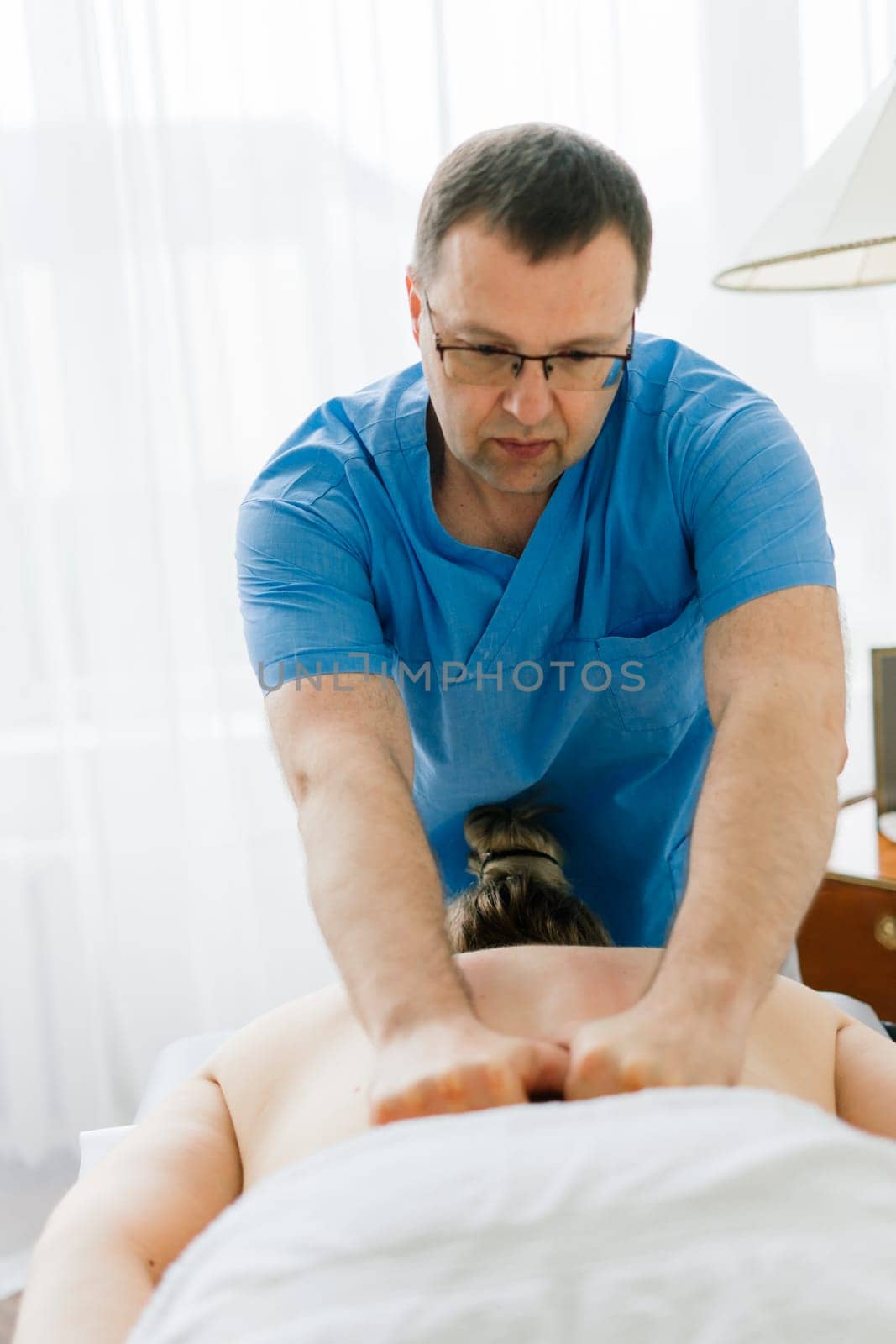 Young fat woman getting massage treatment in day spa cabinet. by Zelenin