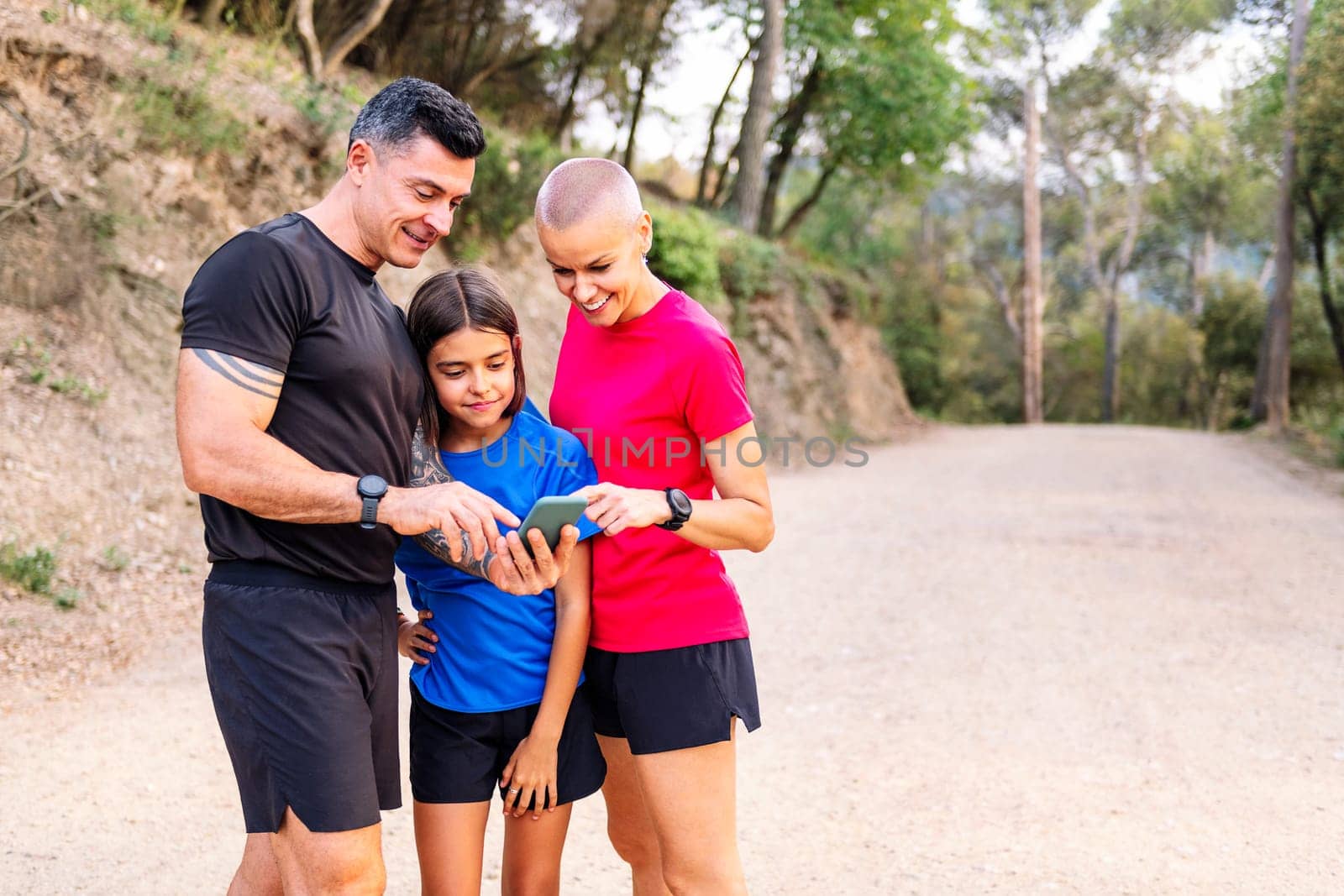 sporty family using a mobile phone to plan their training in the countryside, concept of sport with kids in nature and active lifestyle